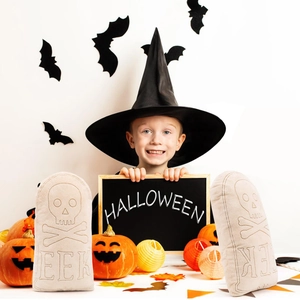 Halloween tombstone plush pillows with skull embroidery and child holding a festive sign