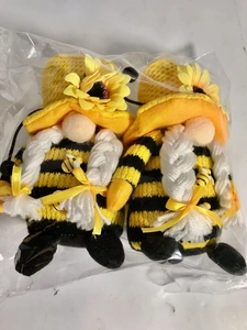 Close-up of cute bee-themed gnomes with sunflower accents in plastic packaging