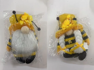Detail of two bee-themed gnome plush toys with yellow flowers and black striped patterns