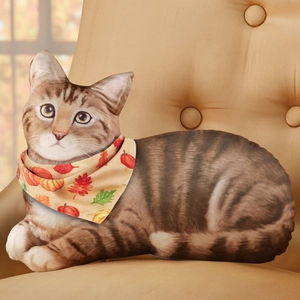 3D cat-shaped decorative pillow with seasonal pumpkin scarf on a cozy sofa