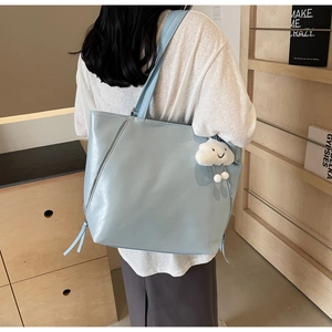 Detail of light blue glossy PU tote bag with silver zipper and white cloud charm accessory