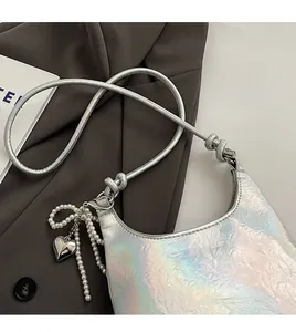 Detail of silver holographic shoulder bag featuring pleated texture and pearl bow charm