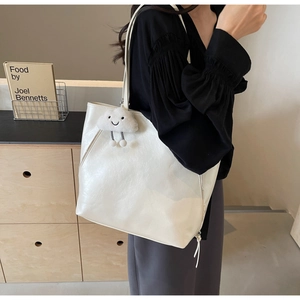 Close-up of white tote bag with glossy finish, side zipper detail and plush cloud charm