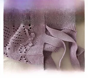 Détail du sac fourre-tout en tricot violet avec motif crocheté ajouré et nœud