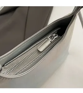 Detail of a smooth silver metal zipper on a pearl gray leather shoulder handbag