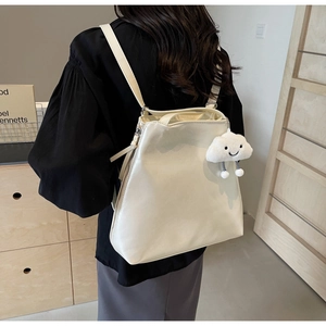 Detail of minimalist beige PU leather backpack with a cute cloud plush charm accessory