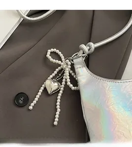 Close-up of metallic silver PU bag featuring a pearl bow knot and heart pendant charm