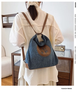 Detail of blue denim and brown leather backpack with SCP leather patch and slim straps
