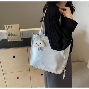 Detail of silver tote bag with leather texture, tassel zipper, and plush cloud charm