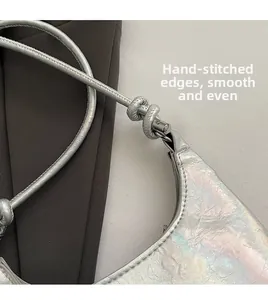 Detail of holographic silver PU leather bag with manual stitching and smooth cylindrical strap