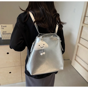 Detail of silver metallic backpack with plush cloud charm and minimalist texture
