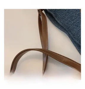 Detailed macro view of denim fabric with brown leather handle and white stitching