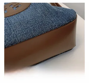 Detailed close-up of navy denim and brown leather stitching on a large tote bag