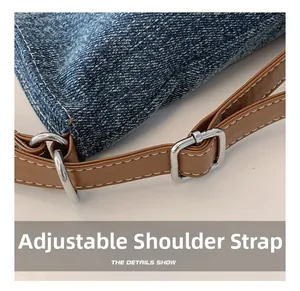 Detail of adjustable leather strap and denim fabric with white contrast stitching