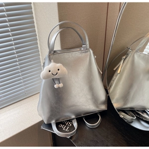 Detail of silver metallic tote bag with plush cloud charm and sturdy top handle