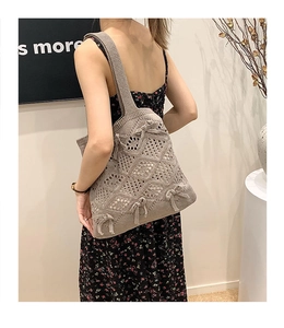 Détail de la maille et du motif ajouré d'un sac cabas gris avec un nœud décoratif