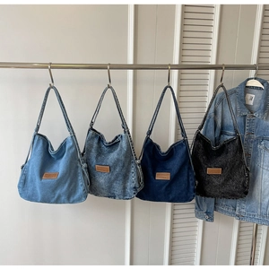 Quattro borse tote in denim in vari lavaggi appese a un'asta di metallo argentata