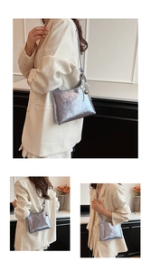 Detail of silver metallic bucket bag with pleated texture and pearl charm on a model