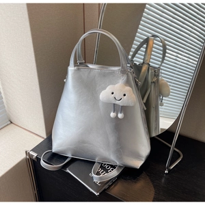 Detail of silver metallic tote bag with cracked texture and plush cloud charm