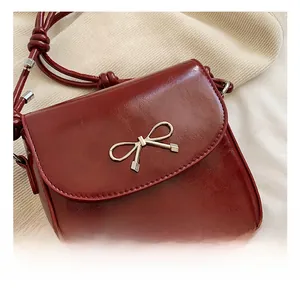 Detailed macro view of the wine red PU leather crossbody bag with silver bow buckle