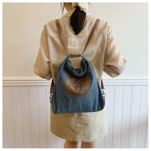 Detail of blue denim backpack showing ZCJP leather patch and adjustable brown straps