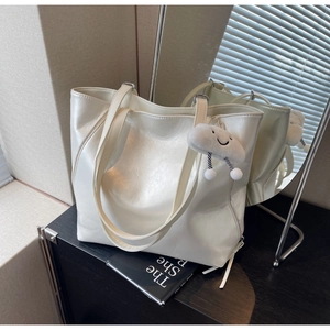 Detail of a large cream tote bag featuring glossy texture and a cute cloud plush charm