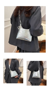 Close-up of silver pleated bucket bag featuring pearl bead charm and metallic finish