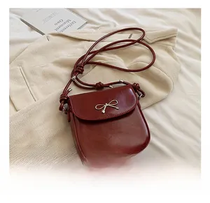Detail of red saddle bag with metal bow accent on striped blazer and book