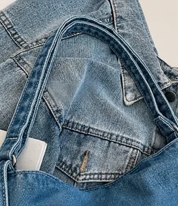 Dettaglio ravvicinato della tracolla larga in denim e fibbia in metallo su borsa lavata