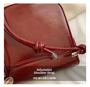 Close-up of adjustable knotted shoulder strap on burgundy leather crossbody square bag