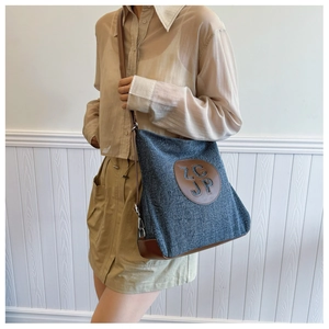 Detail of blue denim shoulder bag with brown leather trim and circular ZCJP leather logo