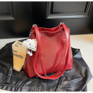 Detail of red glossy tote bag with white cloud plush pendant on a black jacket