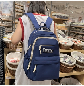 Detailed view of deep blue nylon backpack with RKDBAG logo on a model in a store