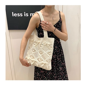 Détail d'un sac cabas en tricot beige avec texture ajourée et nœuds décoratifs fins