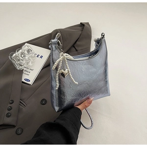 Macro detail of silver textured leather bucket bag with pearl and heart charms