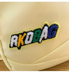 Close-up of the colorful RKOBAG embroidered letter patch on a beige nylon backpack