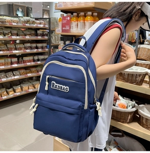 Detail of navy blue student backpack showing RKDBAG logo and white zipper trim