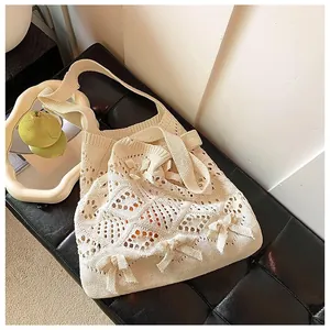 Détail du sac cabas en tricot crème avec motifs en losanges évidés et nœuds décoratifs