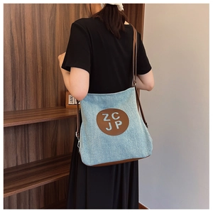 Detail of denim crossbody bag with brown leather patch and white ZC JP letter logo