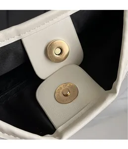 Close-up of white tote bag interior with magnetic gold clasp and fine pebble leather texture