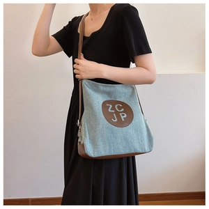 Detail of light blue canvas tote bag with brown leather base and ZCJP logo patch