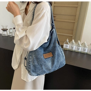 Dettaglio della borsa hobo in denim blu vintage con toppa in pelle e grande capacità di carico