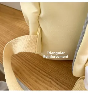 Close-up of triangular reinforced shoulder straps on a light yellow canvas backpack