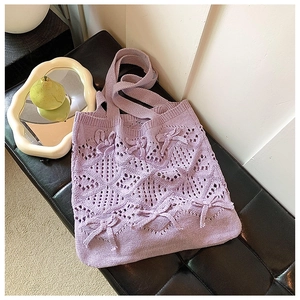 Détail du sac cabas en tricot violet clair avec motifs ajourés et nœuds décoratifs