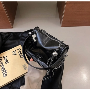 Détail du sac polochon en cuir brillant noir avec chaîne argentée et pendentif cheval