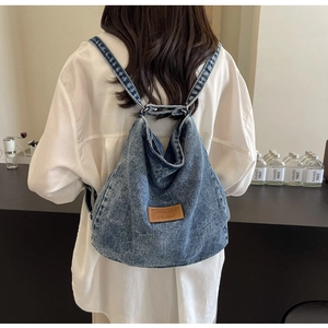 Vista posteriore di una modella con lo zaino in denim azzurro in un caffè accogliente