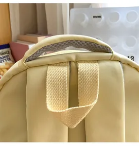 Detail of the cream canvas backpack showing a breathable mesh handle and sturdy stitching
