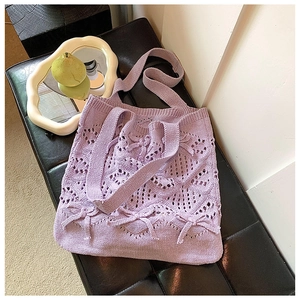 Détail d'un sac cabas en tricot lilas ajouré avec nœuds décoratifs et texture tissée