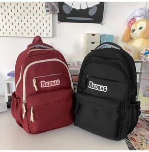 Detail of burgundy and black backpacks with RKDBAG logo and multi-pocket design