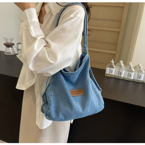 Dettaglio della borsa tote in denim blu lavato con etichetta in pelle in stile casual